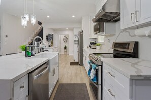 A modern kitchen with white cabinetry, stainless steel appliances, and a central island.