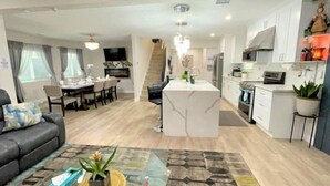 A modern apartment with a dining area, kitchen, and living room.