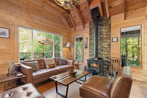 A cozy cabin interior with a wooden interior, a stone fireplace, a sofa, and a dining table. - PNW River Cabin • Hot Tub • Firepit • Fireplace (Snohomish County)
