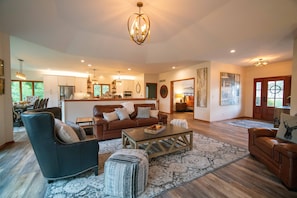 A spacious living room with a brown leather sofa, a coffee table, and a patterned rug.