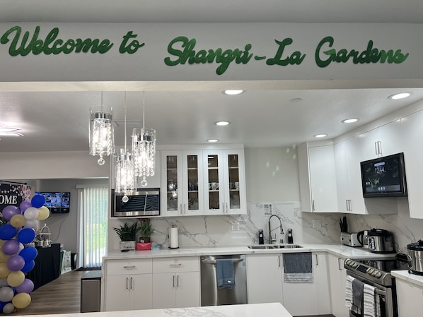A modern kitchen with white cabinets, a marble backsplash, and stainless steel appliances.