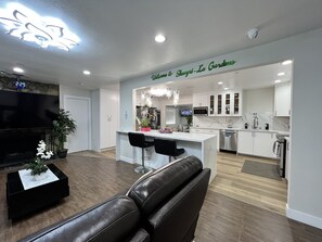 A modern living room with a leather sofa, a TV, and a dining area with a bar. - Secluded/Quiet Home-CherryValley (Cherry Valley)