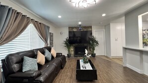 Una sala de estar moderna con un sofá de cuero, una mesa de centro, una chimenea y un televisor de pantalla plana.