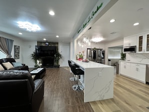 A modern kitchen with white cabinets, a marble countertop, and stainless steel appliances.