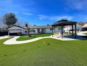 A residential property with a well-maintained lawn, a gazebo, and a garage.