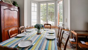 Un comedor con mantel a rayas, sillas de madera y un jarrón con flores.