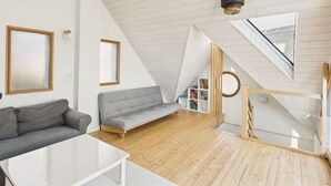 A modern loft bedroom with a sloped ceiling, a built-in bookshelf, a grey sofa, and a white coffee table. - Sea view - House for 7 with balcony (Saint-Pierre-Quiberon)