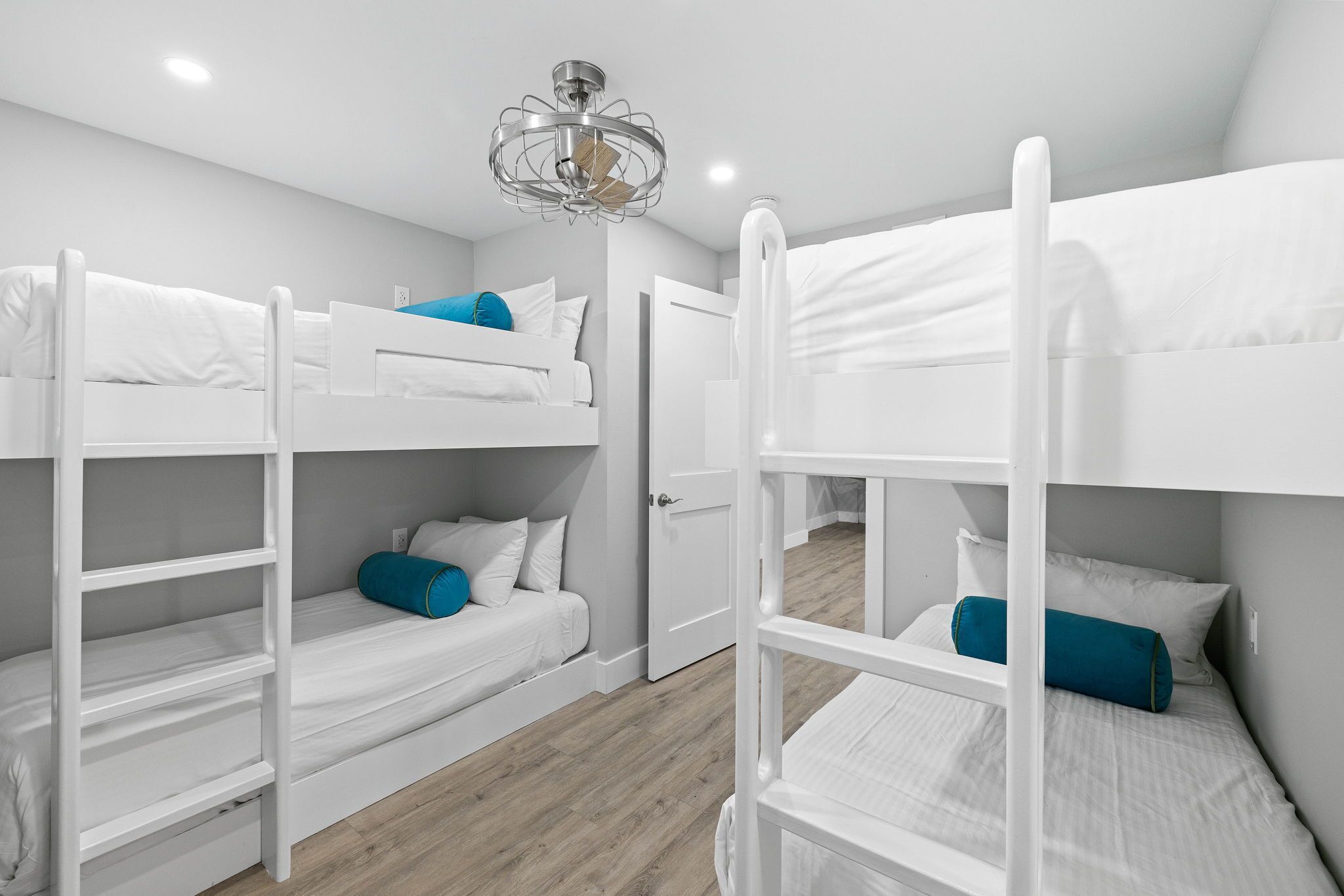 Une pièce avec des lits superposés, une porte et un luminaire au plafond.