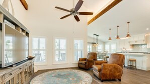 A spacious living room with a large round rug, wooden flooring, and a ceiling fan. - Private Pool, Gas Grill, 2 Smokers, Boat Slip, Huge Deck & Patio & More! (Jamaica Beach)