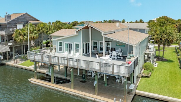 A waterfront house with a deck, outdoor seating, and a view of the water. - Private Pool, Gas Grill, 2 Smokers, Boat Slip, Huge Deck & Patio & More! (Jamaica Beach)