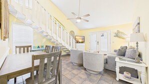 A spacious living area with a staircase, a dining table, and a sofa.