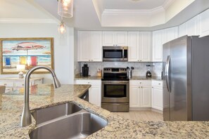 A modern kitchen with white cabinets, stainless steel appliances, and a granite countertop.