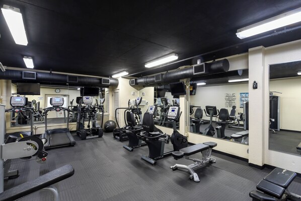 A gym with various exercise equipment, mirrors, and a clock on the wall. - Gulf View Retreat with Beach Service at Sterling Shores (Destin)