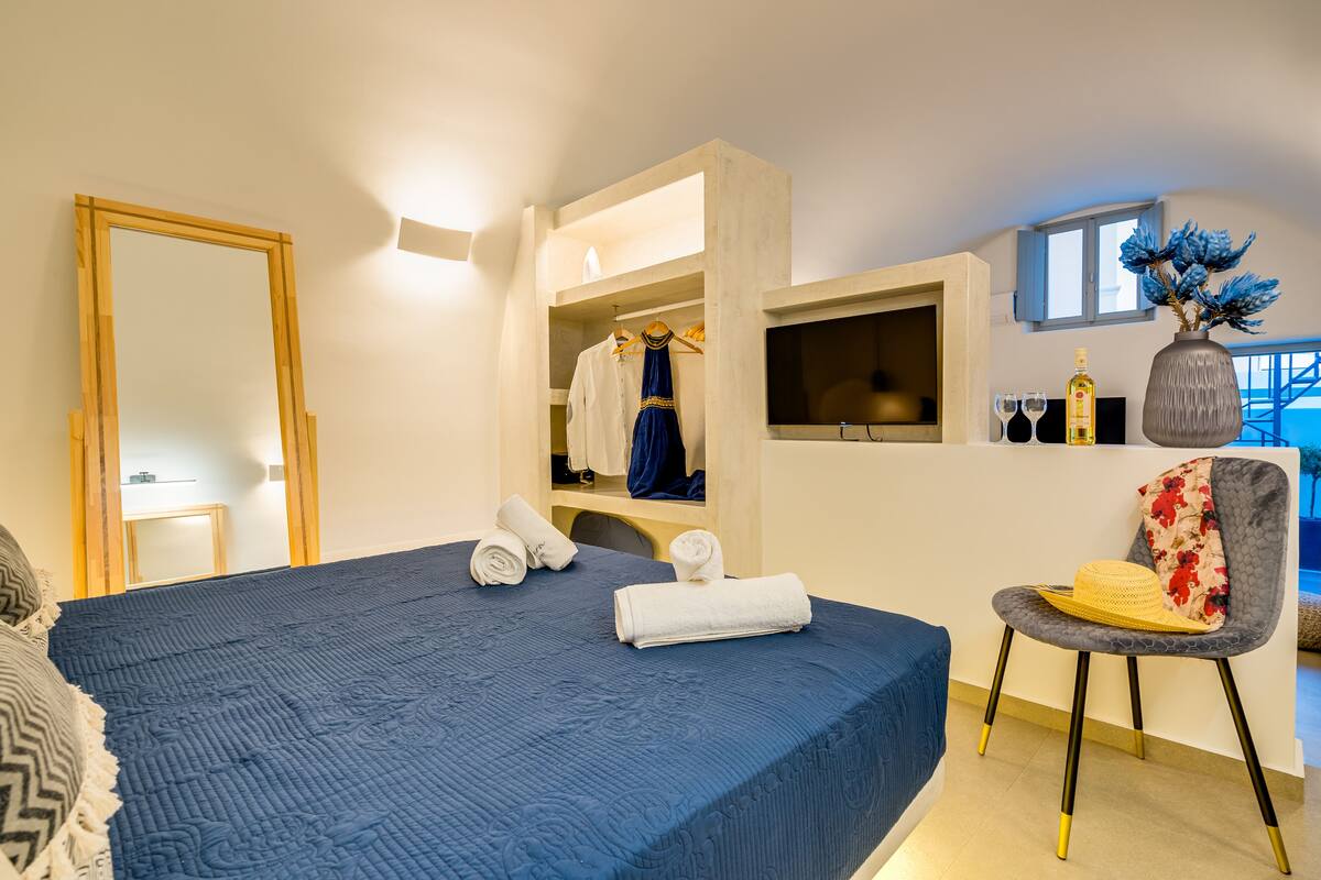 A bedroom with a bed, a chair, a wardrobe, and a mirror.
