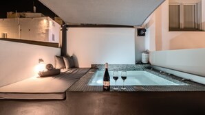 A modern bathroom with a glass-enclosed hot tub, a bottle of wine, and two glasses on a tray. - Tiara Suites (Santorini)