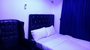 A room with a bed, a chair, and an air conditioning unit on the wall. - SMD Hotel and Suites (Port Harcourt)