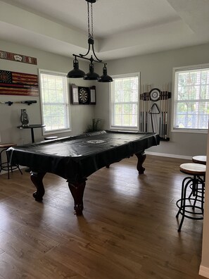 Relax in this spacious room featuring a pool table, high ceiling, and large windows.