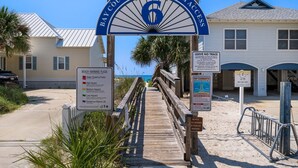 A wooden boardwalk leading to a beach entrance with a sign indicating beach access number 6. - Steps to beach w/ pool and daily attraction perks (Panama City Beach)