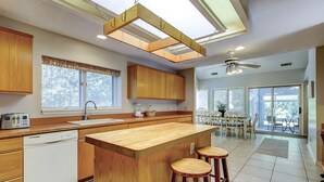 A spacious kitchen with wooden cabinets, a central island with stools, a dishwasher, and a ceiling fan. - Sunset Rentals | Off Shore 16 (Hilton Head Island)