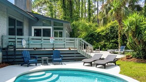 A pool area with lounge chairs, a small table, and a staircase leading to a building. - Sunset Rentals | Off Shore 16 (Hilton Head Island)