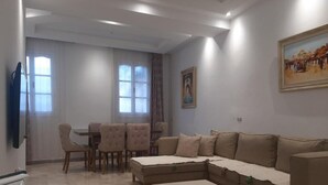 Una sala de estar con un sofá, una mesa de centro, una mesa de comedor con sillas y un cuadro en la pared.