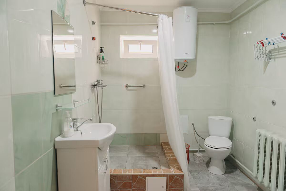 Une salle de bain avec douche, toilettes et lavabo.
