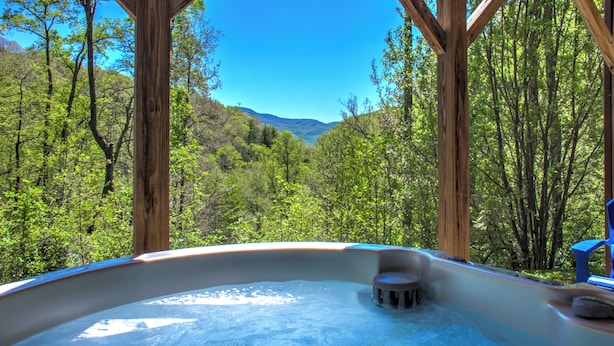 Un bain à remous situé dans une zone boisée, avec vue sur une vallée.