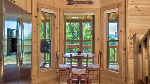 L’intérieur d’un chalet en bois comprend une table à manger et des chaises, un réfrigérateur et un panneau indiquant : « Privilégiez les produits locaux ».
