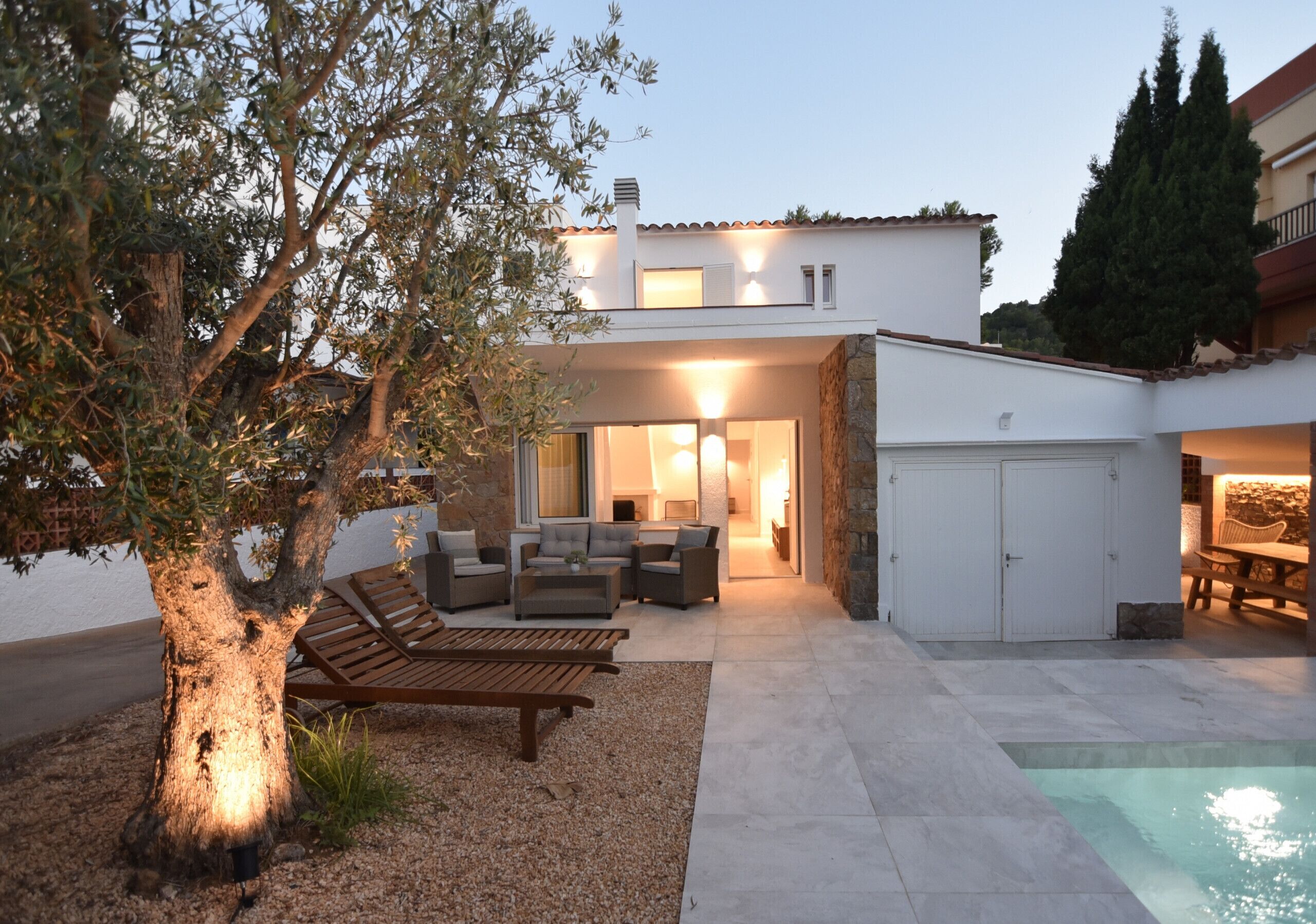 A modern house with a patio, outdoor seating, and a swimming pool.
