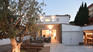 Een modern huis met een terras, buitenmeubels en een zwembad.