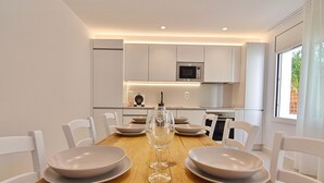 Een moderne eetruimte met een houten tafel, witte stoelen en een centraal geplaatst wijnglas.