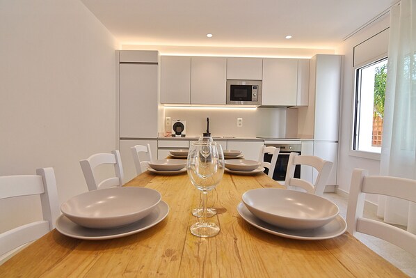 Een moderne eetruimte met een houten tafel, witte stoelen en een centraal geplaatst wijnglas.