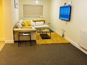 A living room with a sofa, a coffee table, a TV, and a radiator.
