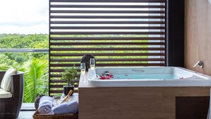 A balcony with a hot tub, a wicker chair, and a small table with a glass of wine and a bottle.