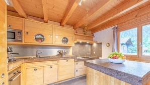 A kitchen with wooden cabinets, a granite countertop, and a bowl of fruit.