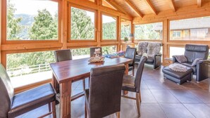 A wooden interior with a dining table and chairs, a sofa, and a fireplace.