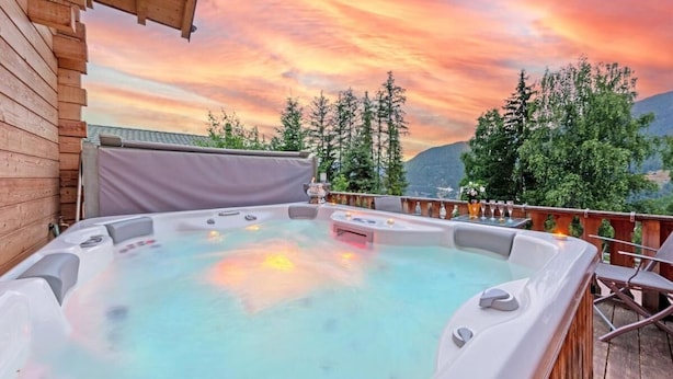 A hot tub on a wooden deck with a scenic mountain view.