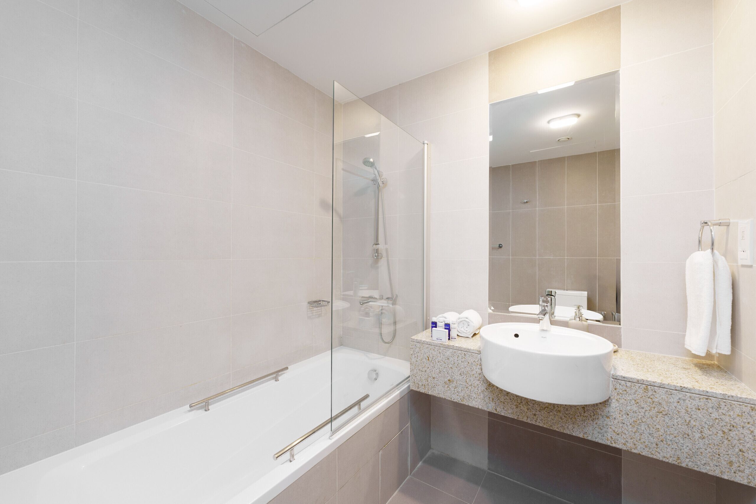 A modern bathroom with a glass-enclosed shower, a freestanding bathtub, and a sink with a countertop.