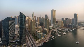 Un paysage urbain dominé par de hauts immeubles, avec une architecture moderne, un port de plaisance rempli de bateaux et un ciel dégagé.
