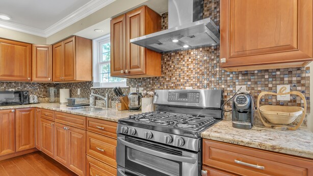 A modern kitchen with wooden cabinets, a stainless steel stove, and a tiled backsplash. - Leo Farm Villa - Beautiful Country Retreat 5 Bedroom Villa by RedAwning (Bel Alton)