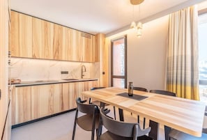 Una cucina moderna con mobili in legno, un piano di lavoro in marmo e un'area pranzo con tavolo e sedie in legno.