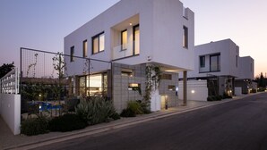 Uma casa moderna de dois andares com telhado plano, janelas amplas e área externa coberta.