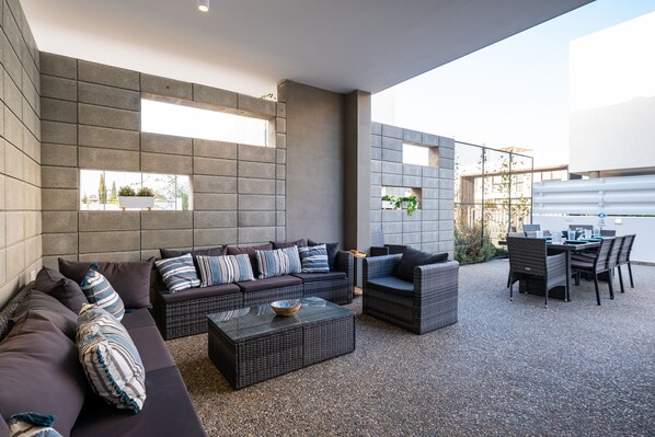 An outdoor patio with a sofa set, a dining table with chairs, and a small coffee table.