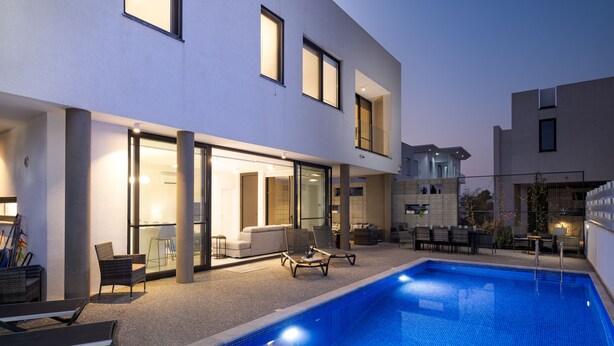 Uma área moderna com piscina ao ar livre, espreguiçadeiras e um pátio bem iluminado.