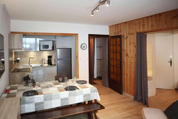 A compact kitchen with modern appliances, a dining area with a checkered tablecloth, and a wooden interior. - Ski-in/ski-out & foot of the slopes, 1st floor, view ski slopes, balcony, tv, 40m², Les Orres (Les Orres)
