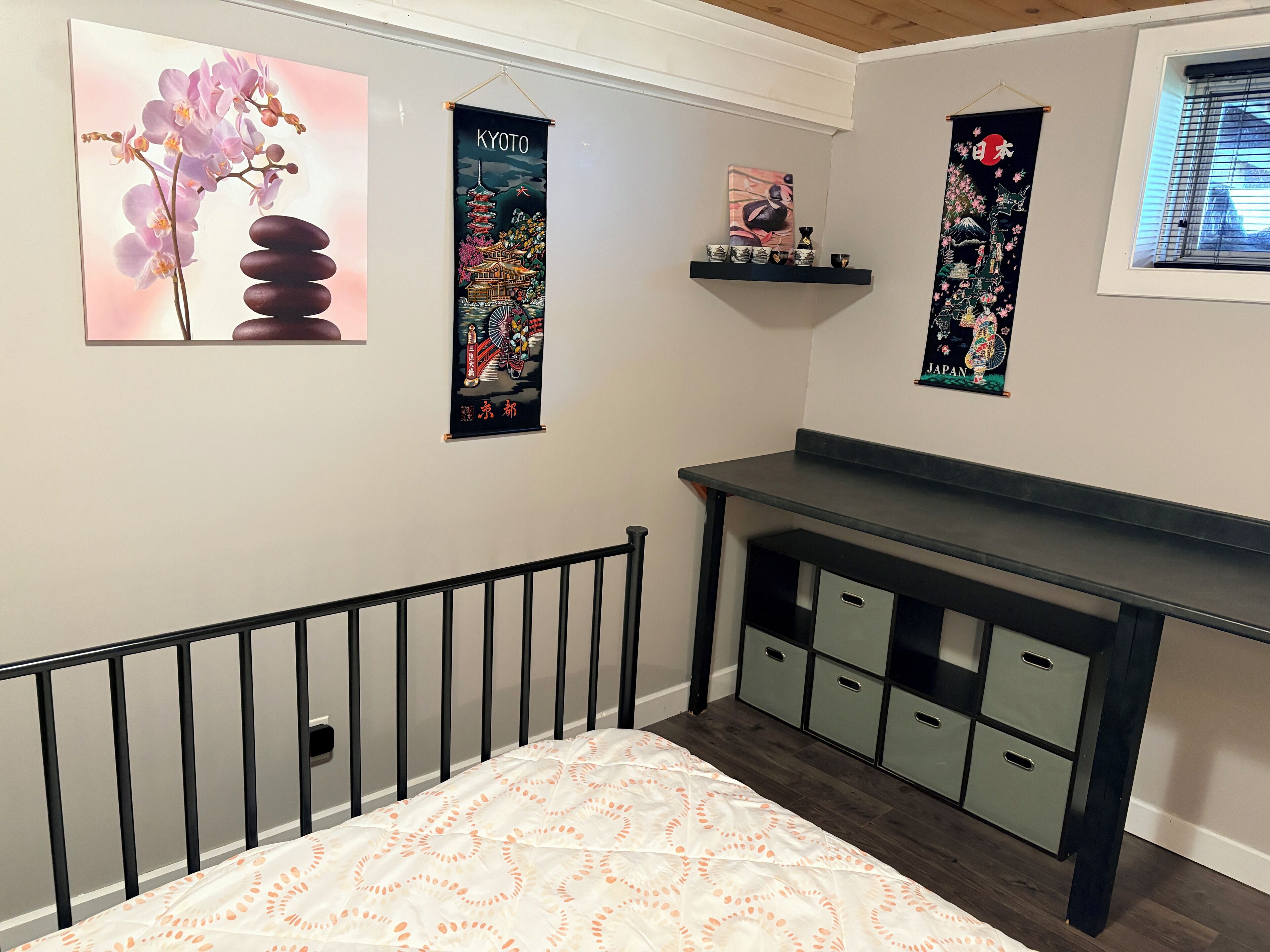 Un dormitorio con una cama, un escritorio y obras de arte en las paredes.