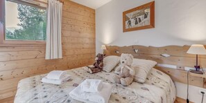 A wooden-paneled bedroom with a bed, two teddy bears, a framed picture, and a bedside lamp. - 2nd floor, fitness, swimming pool, sauna, hammam, terrace, parking, tv, 58m², Champagny-en-Vanoise (Champagny-en-Vanoise)