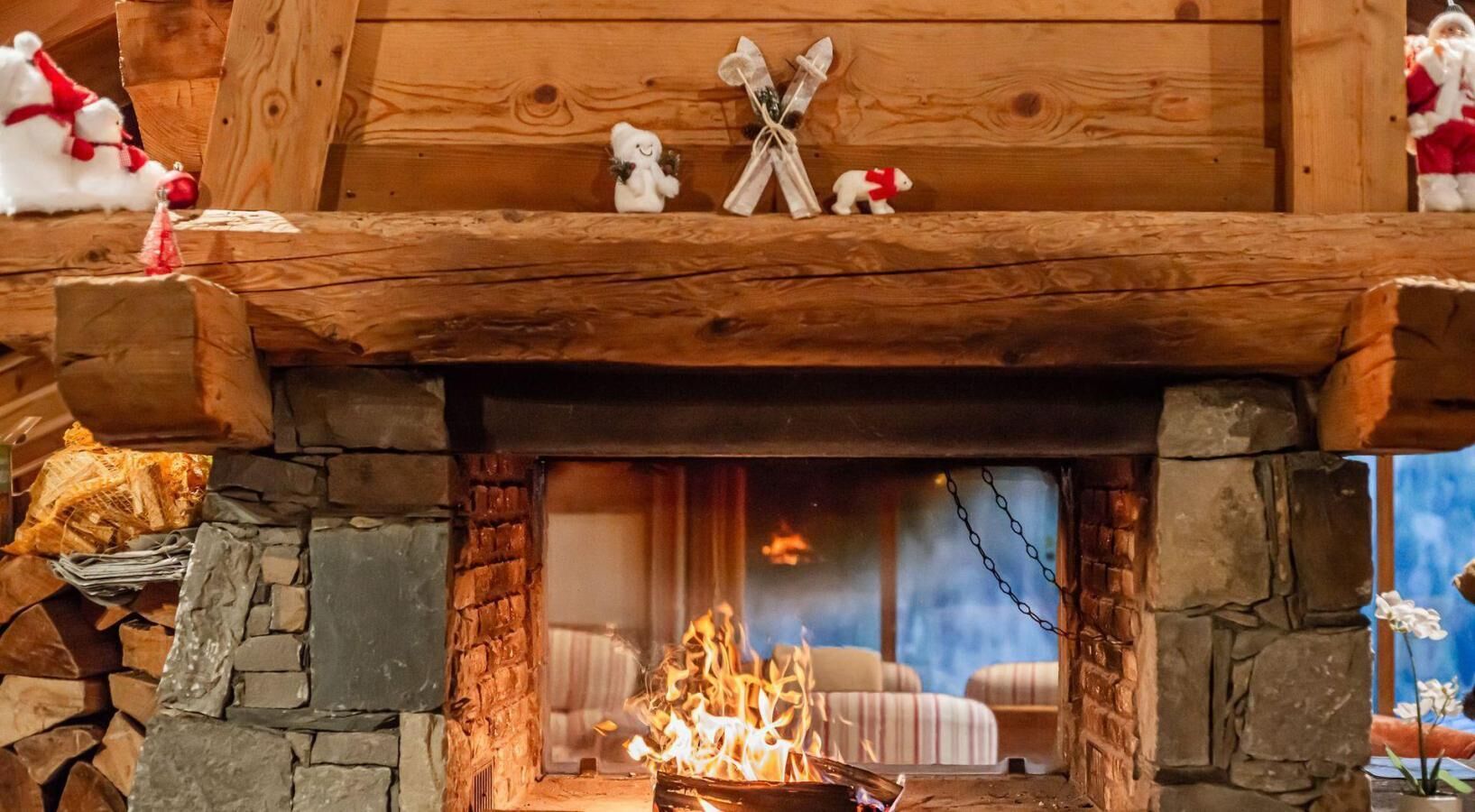 Una chimenea con revestimiento de piedra, repisa de madera y dos pequeñas figurillas.