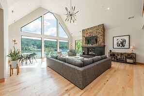 Relax in this spacious living room with a high ceiling and stunning views of the lush landscape.