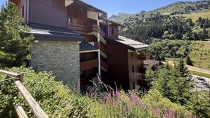 A multi-story building with a stone base, wooden upper floors, and balconies. - 180m from ski slopes, floor -1, view mountain, balcony, tv, 37m², Méribel-Mottaret (Méribel - Les Allues)